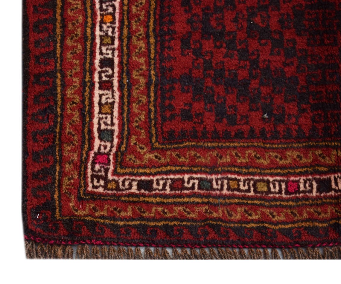 A vintage Afghan Baluch rug featuring a dark red geometric pattern with ivory and brown borders.