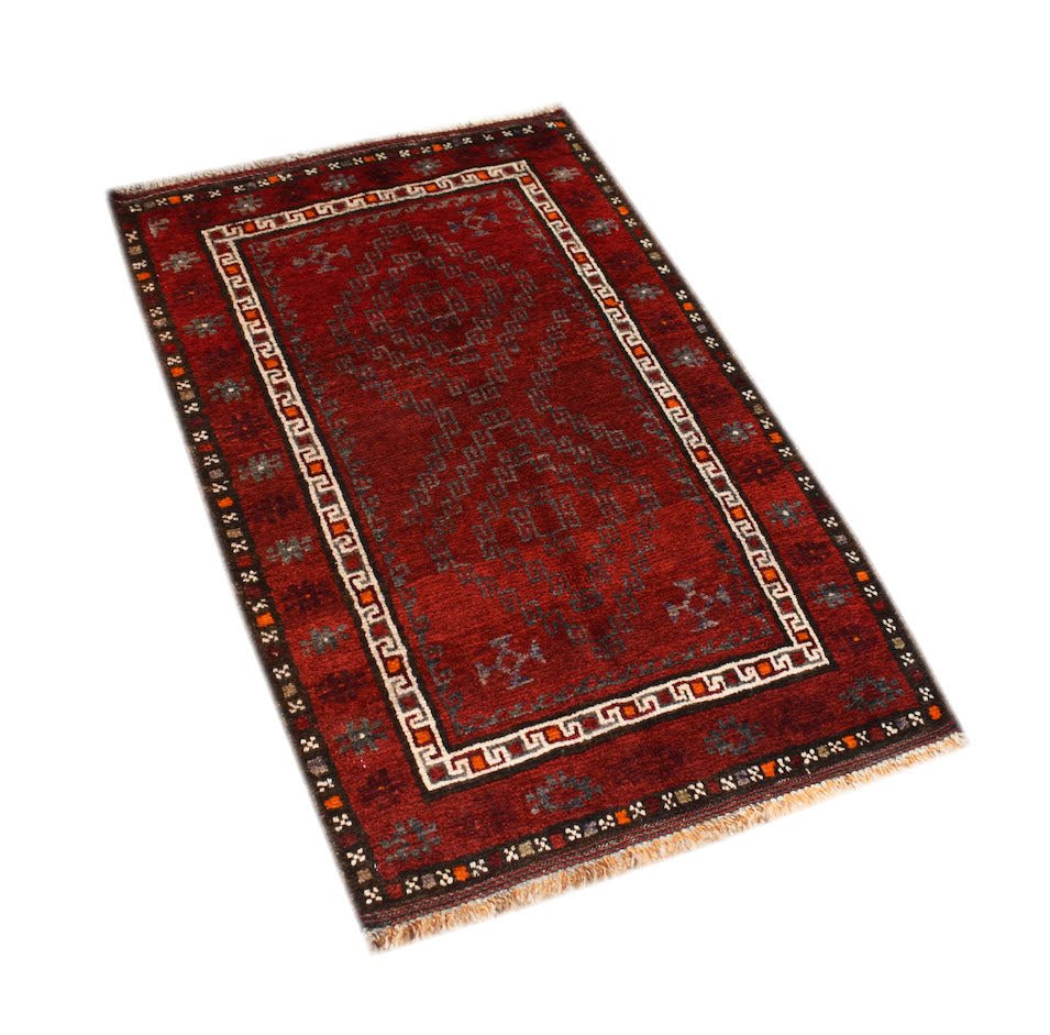 A vintage Afghan Baluch rug featuring a deep red field with geometric patterns and a fringed edge.
