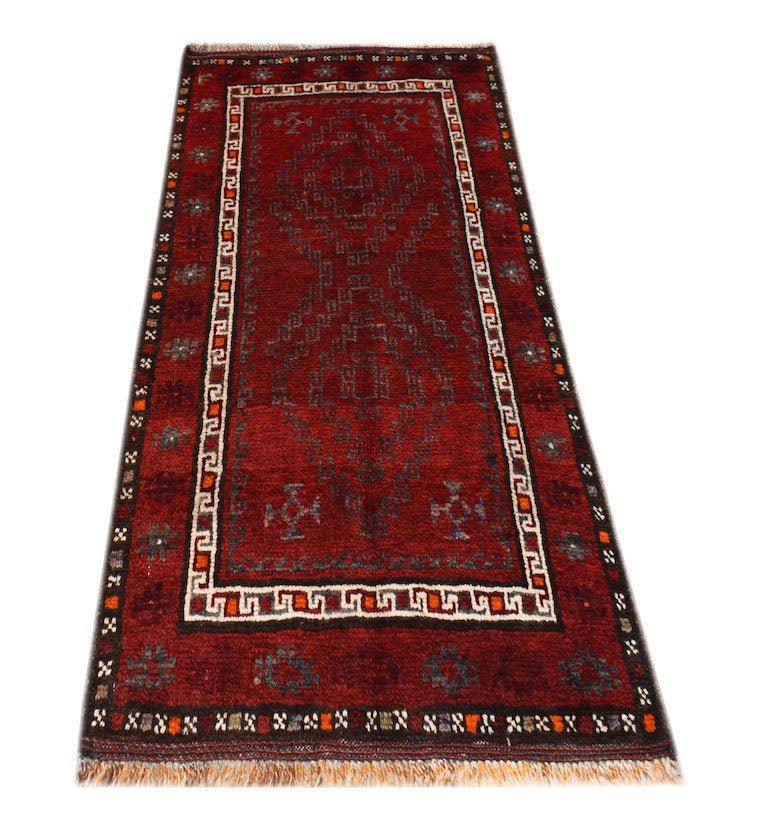 A vintage handmade Afghan Baluch rug featuring a deep red field with geometric diamond patterns.