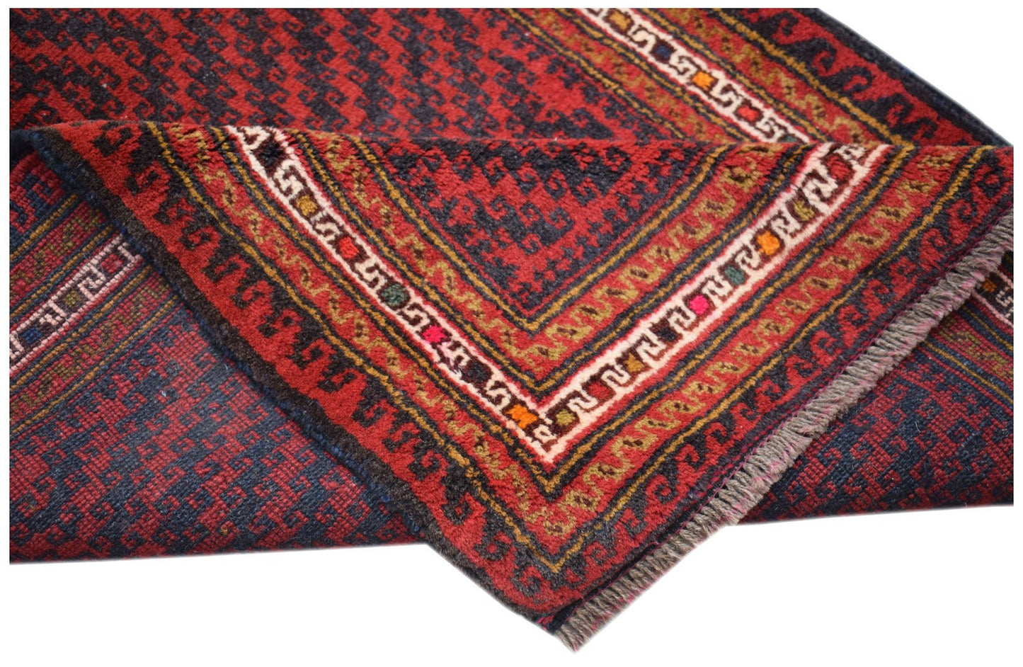 A folded vintage Afghan Baluch rug featuring a geometric pattern in deep red, blue, and brown.