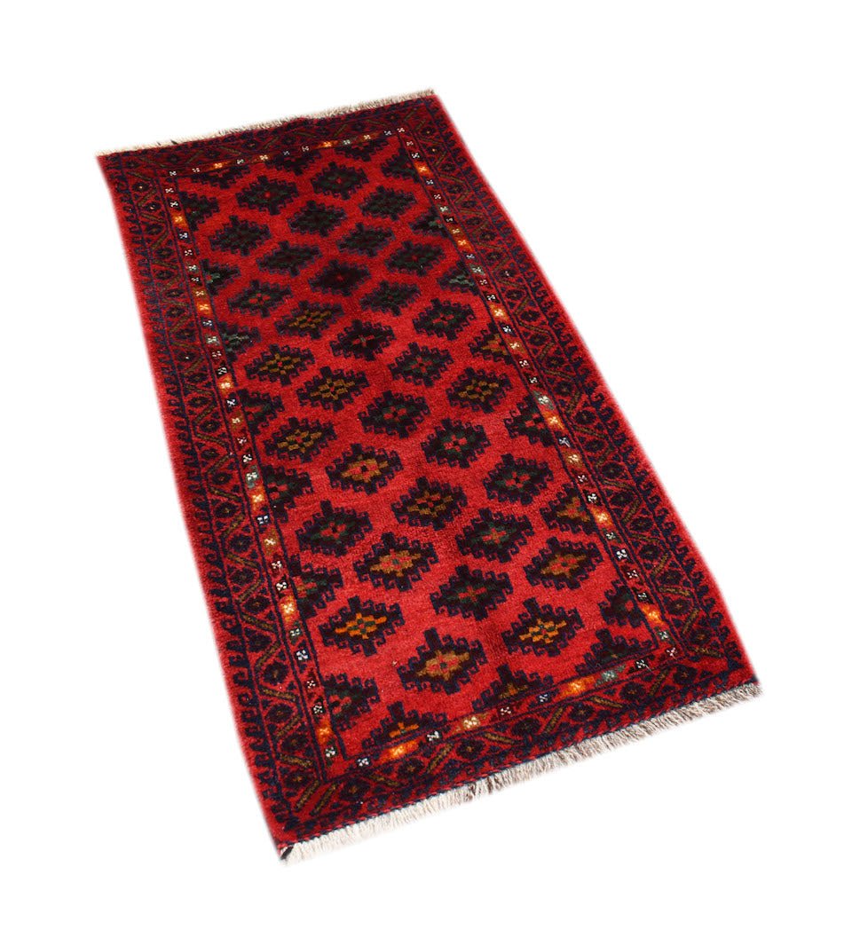 A vintage handmade Afghan Baluch rug featuring a repeating geometric pattern in red and dark tones.