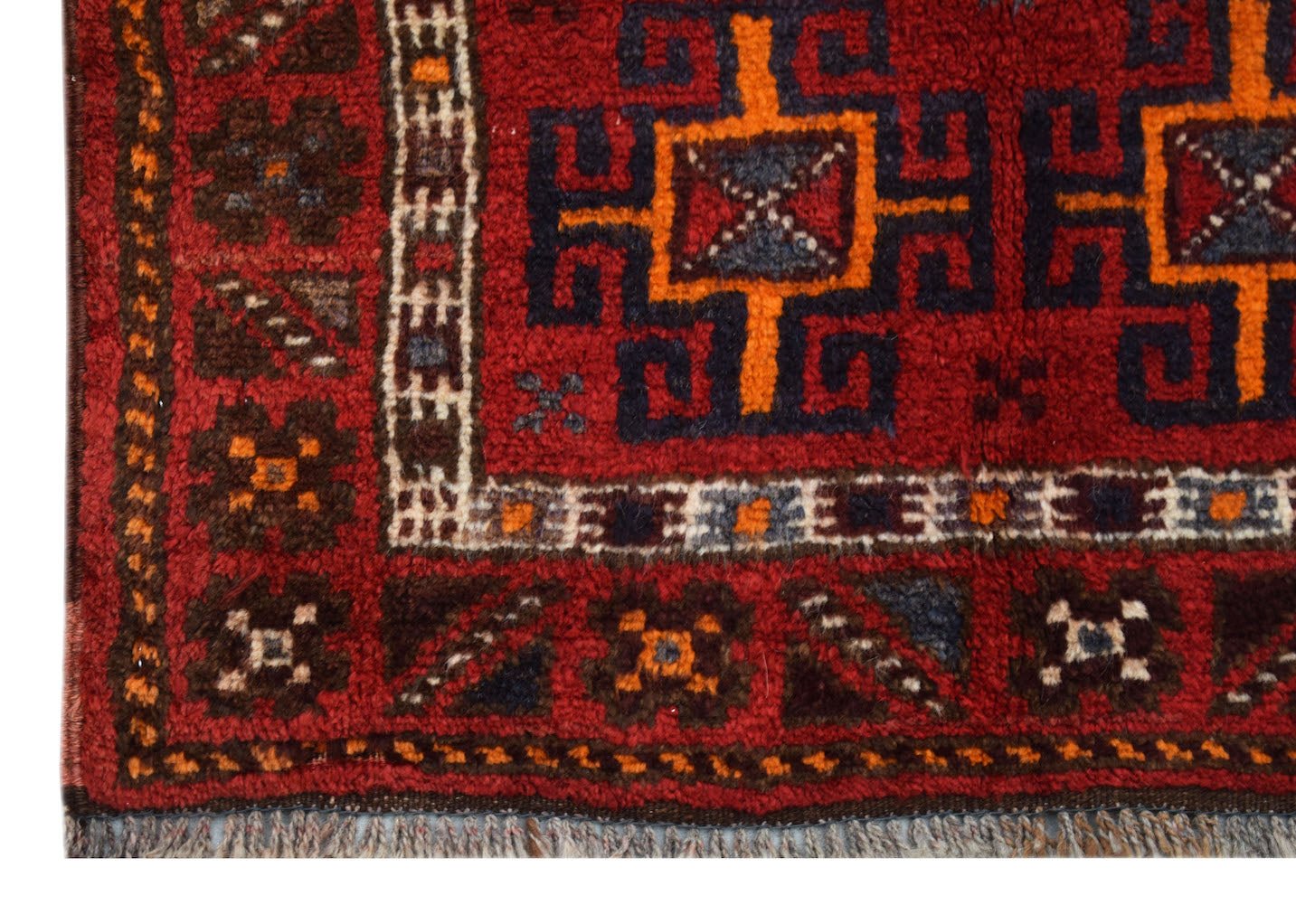A vintage Afghan Baluch rug featuring geometric patterns in red, orange, and dark blue wool.