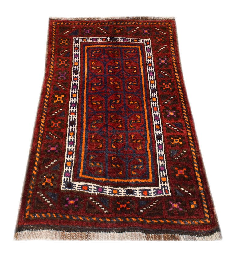 A vintage handmade Afghan Baluch wool rug featuring a geometric pattern in deep red and blue tones.