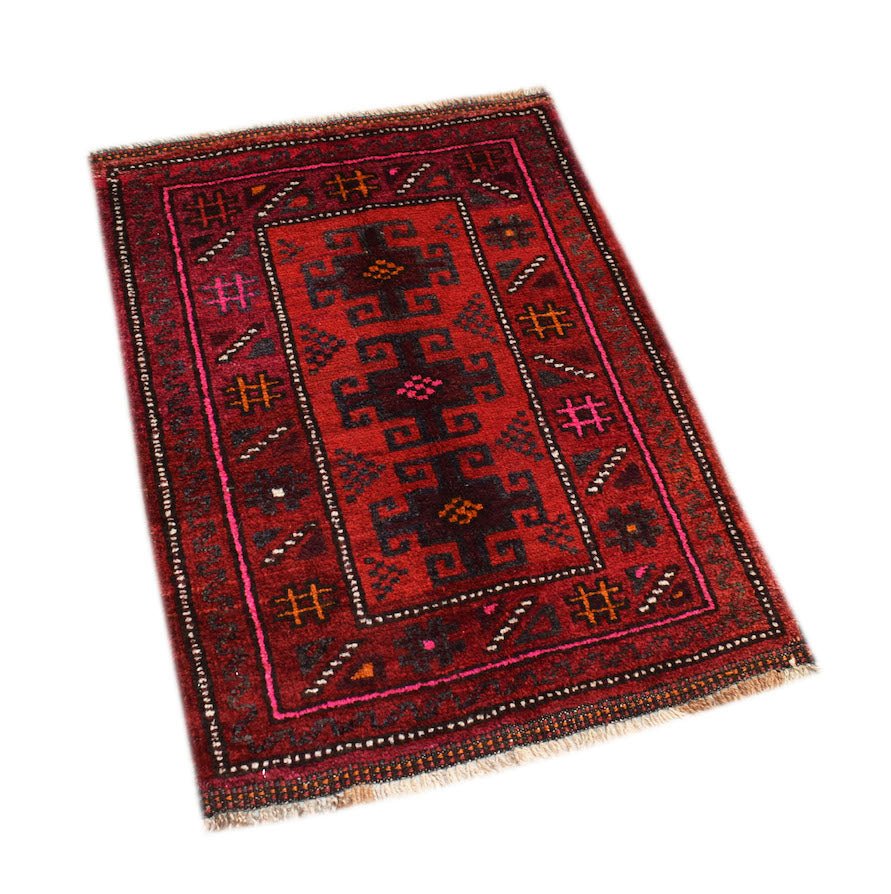A handmade vintage Afghan Baluch rug featuring geometric tribal patterns in deep red and dark tones.