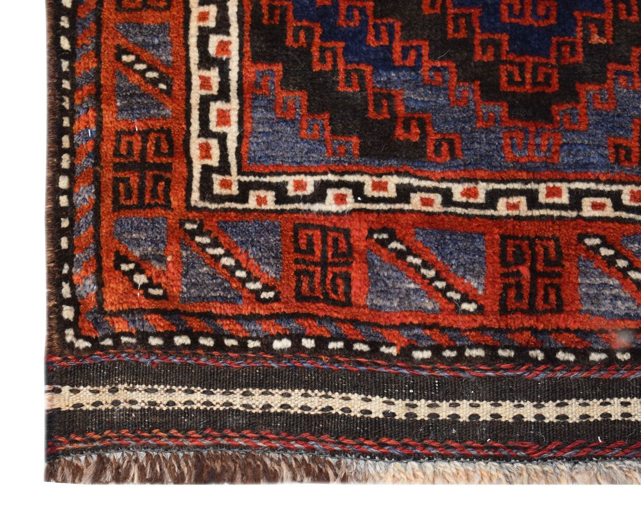 A corner detail of a vintage Afghan Baluch rug featuring geometric patterns in red, blue, and black.