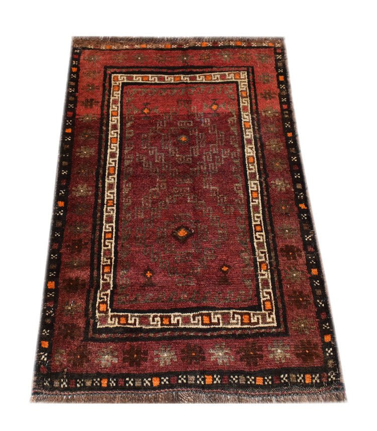A handmade vintage Afghan Baluch rug featuring geometric patterns in deep red, brown, and orange.