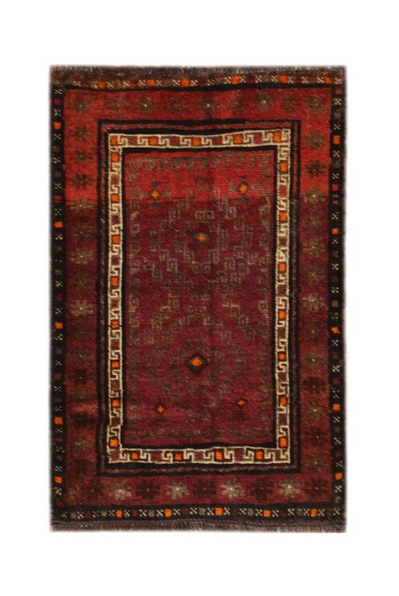 A handmade vintage Afghan Baluch rug featuring geometric patterns in deep red and brown tones.