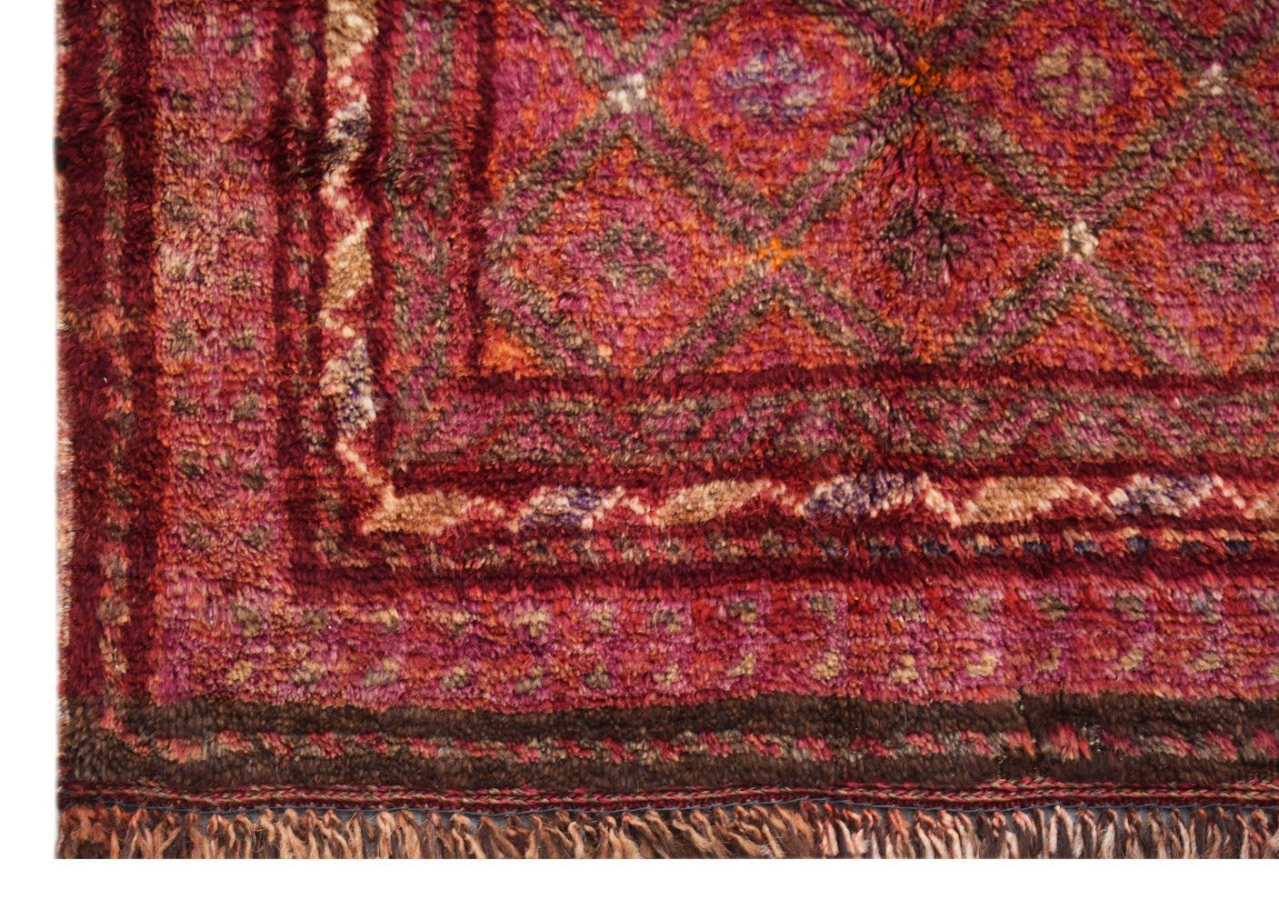 A vintage Afghan Baluch rug featuring a deep red diamond pattern and a fringed edge.