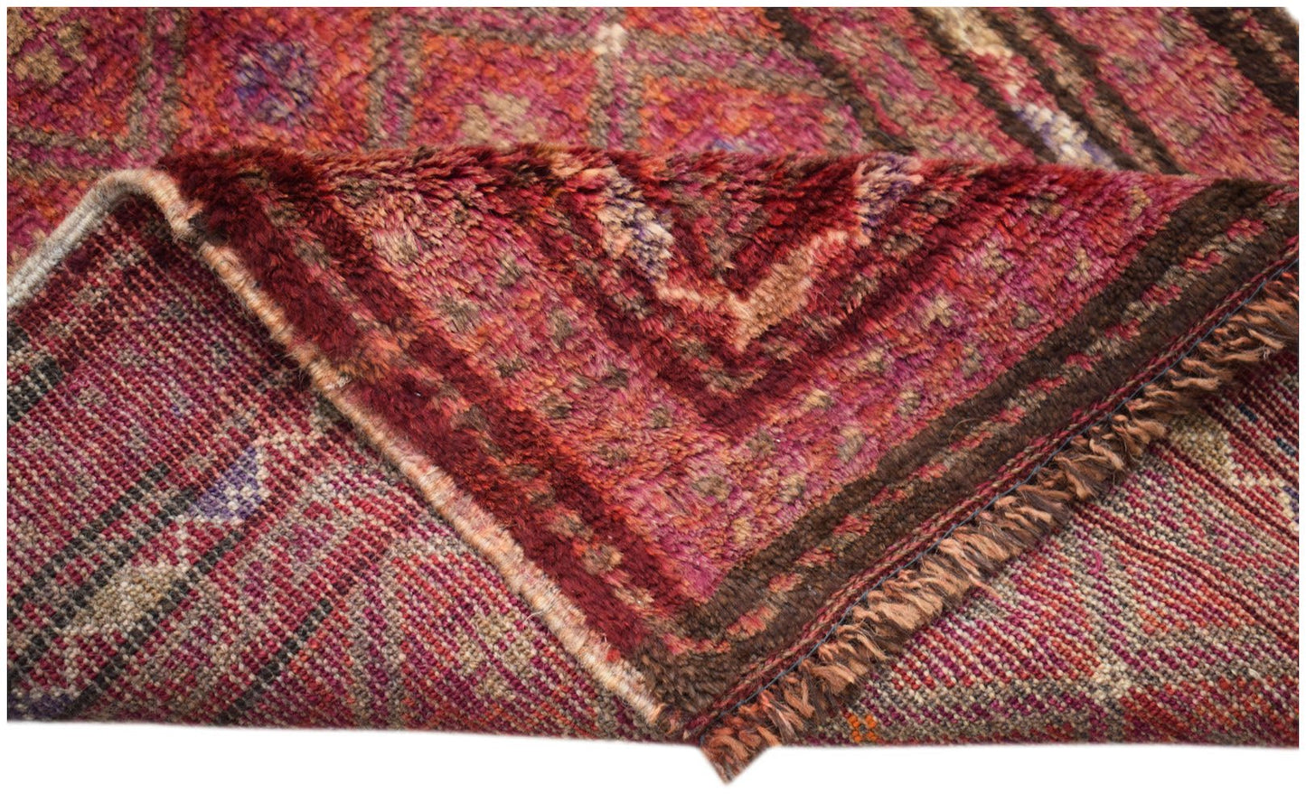 A vintage handmade Afghan Baluch wool rug featuring a deep red geometric pattern and fringe.