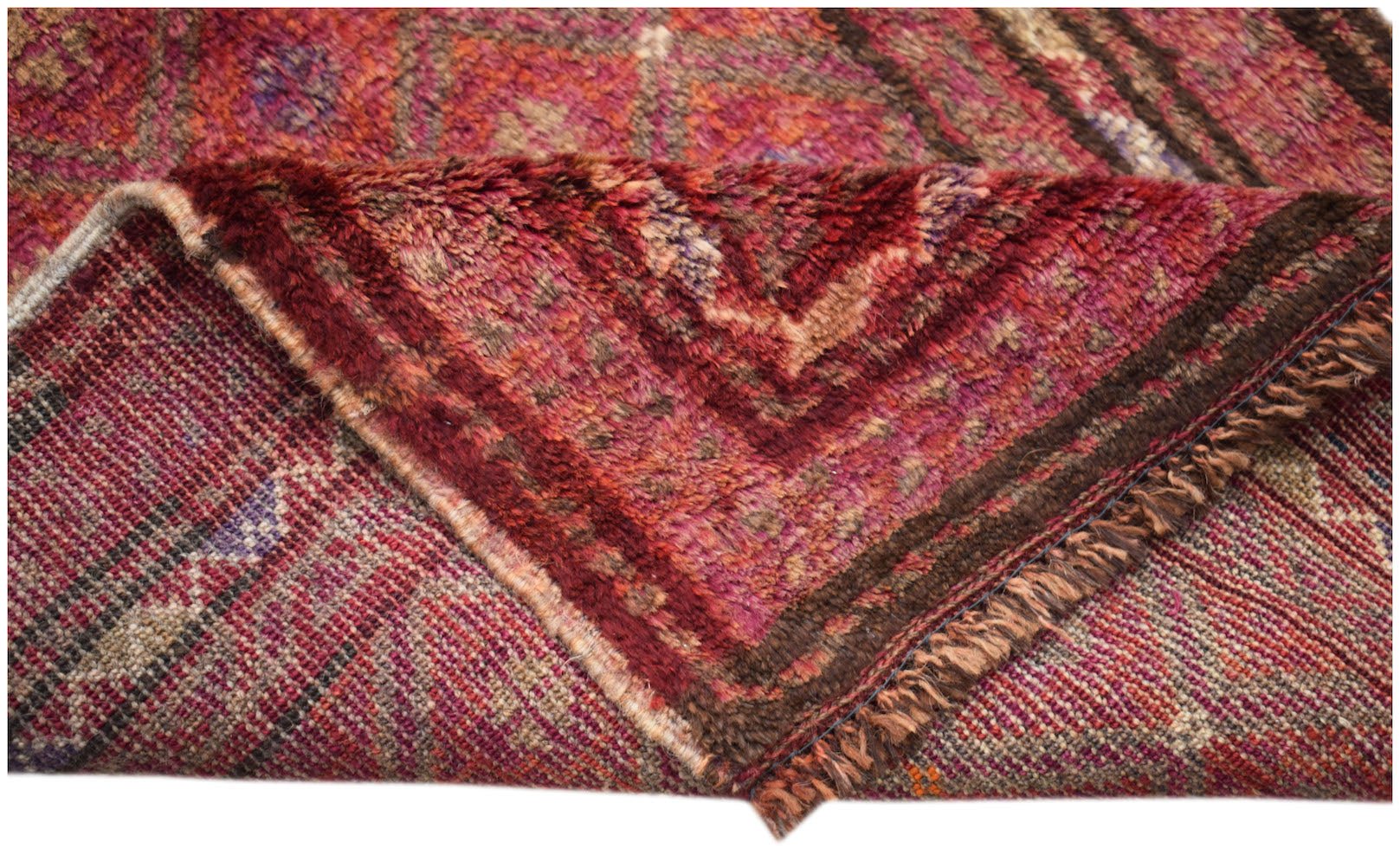 A vintage handmade Afghan Baluch wool rug featuring a deep red geometric pattern and fringe.