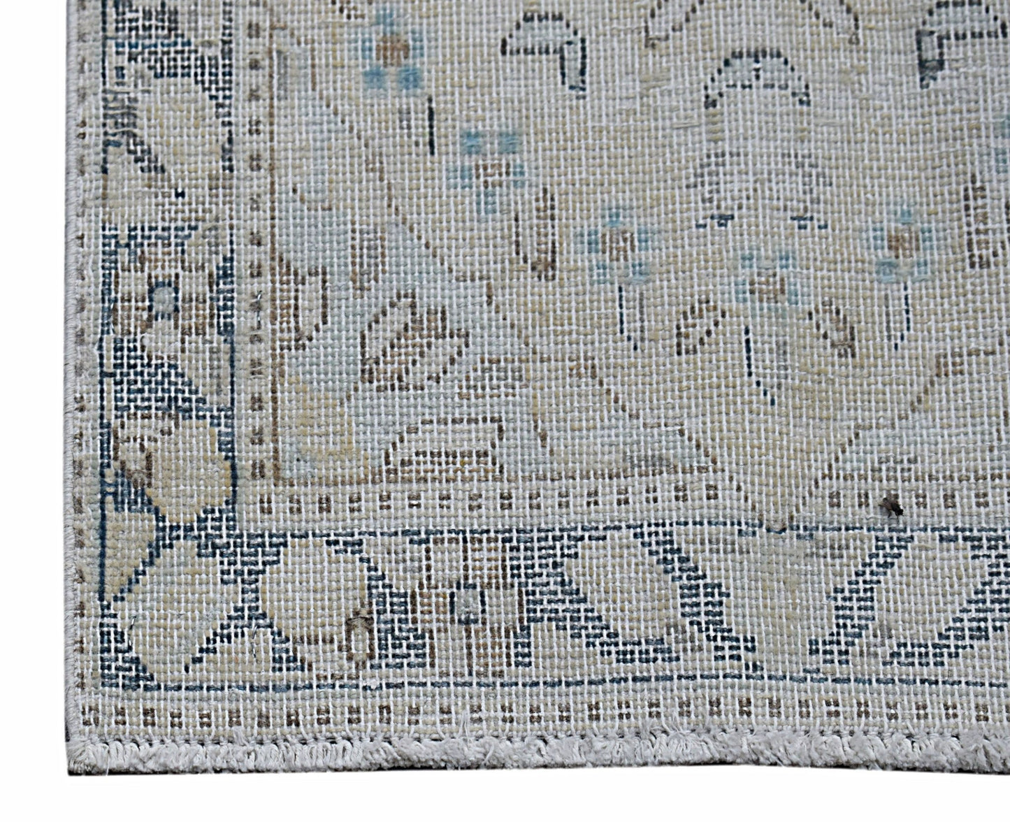 A close-up of a vintage Persian Kerman rug featuring intricate floral patterns in blue and beige.