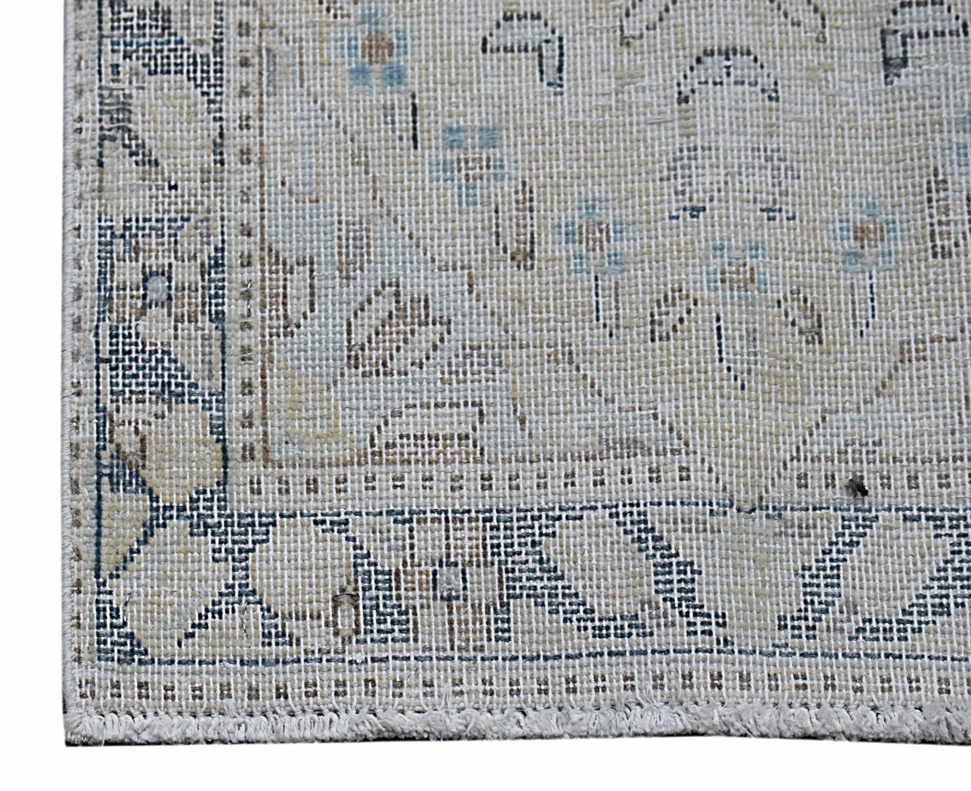 A close-up of a vintage Persian Kerman rug featuring intricate floral patterns in blue and beige.