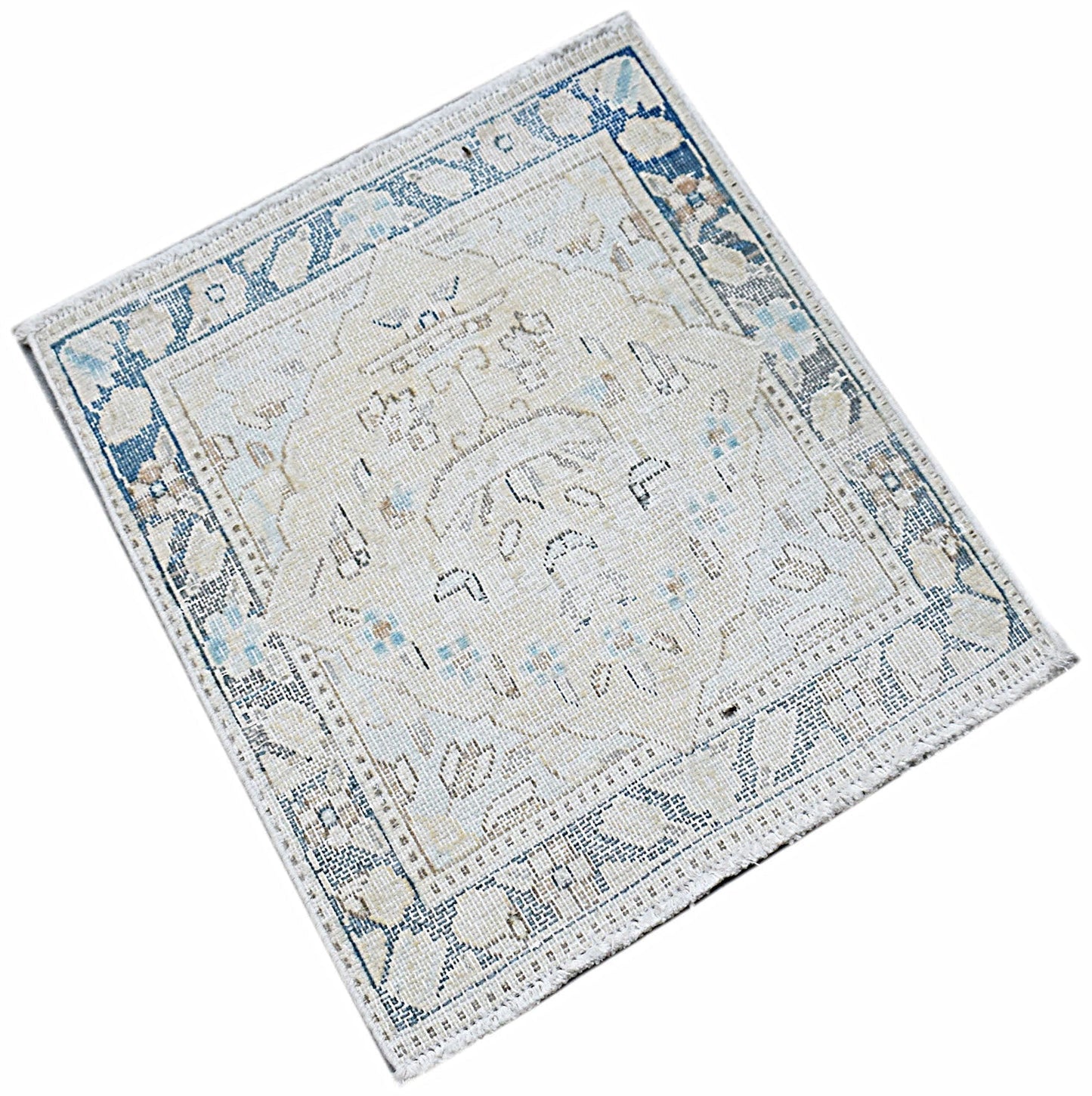 A mini vintage Persian Kerman rug featuring a central medallion and floral motifs in blue and cream.