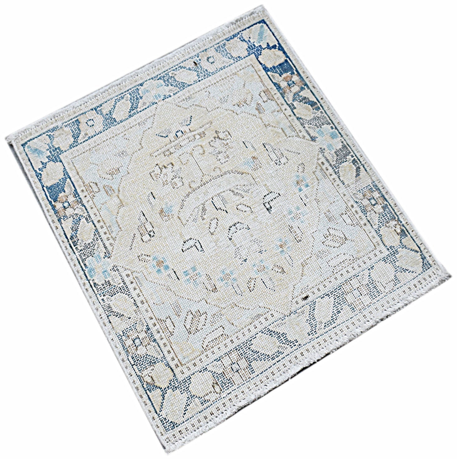 A mini vintage Persian Kerman rug featuring a central medallion and floral motifs in blue and cream.