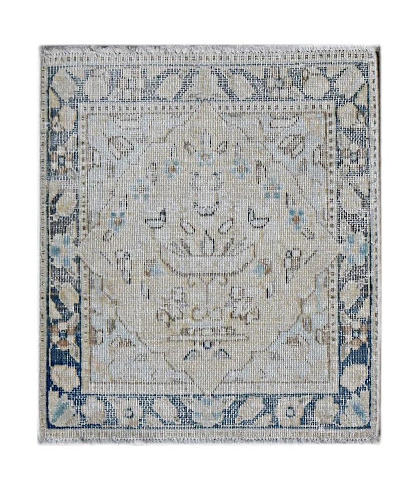 A mini vintage Persian Kerman rug featuring a central floral medallion in soft blue and beige tones.