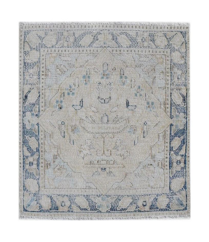A mini vintage Persian Kerman rug featuring a central medallion in soft blue and beige tones.
