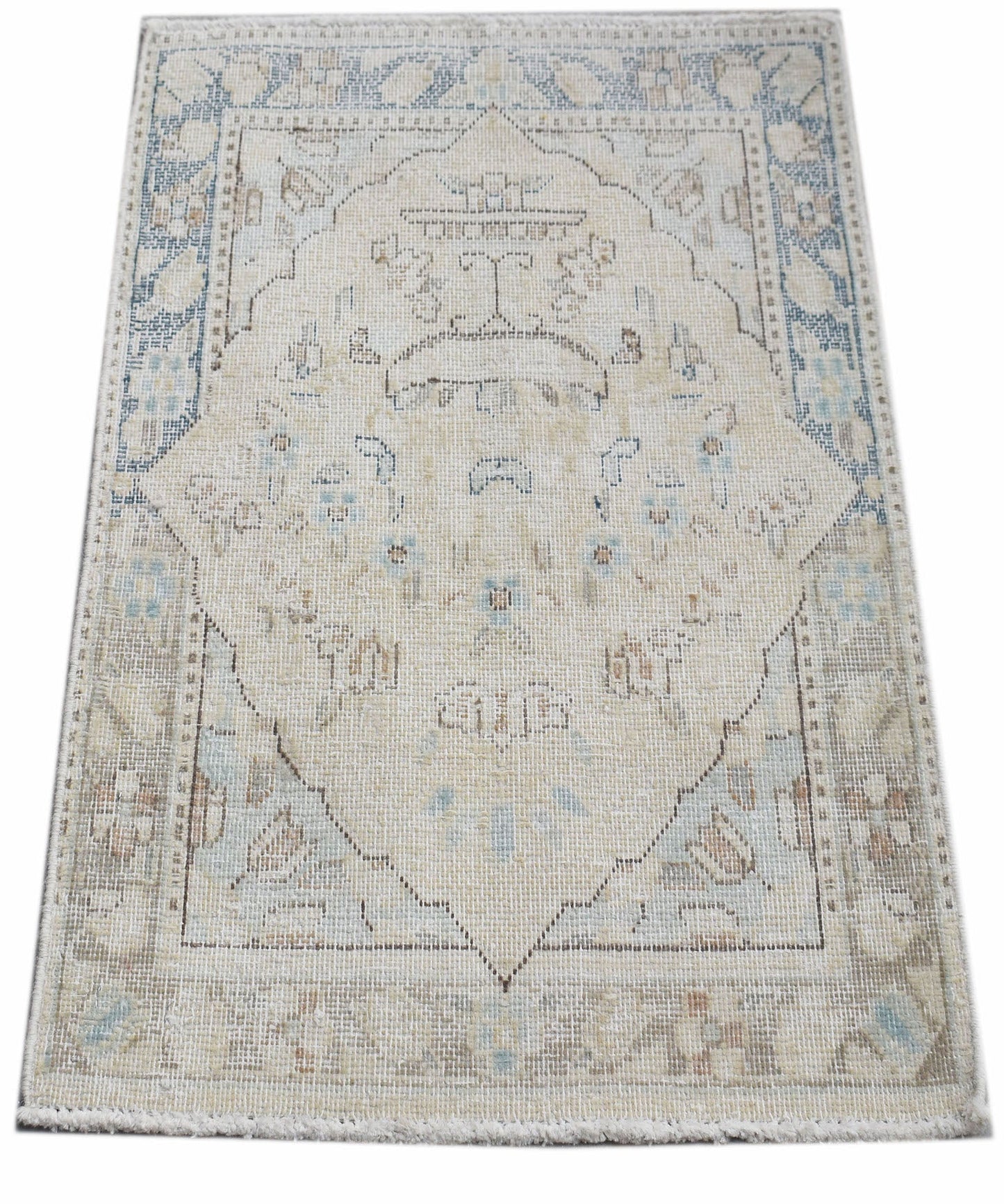 A mini vintage Persian Kerman rug featuring a central medallion in soft blue and beige tones.