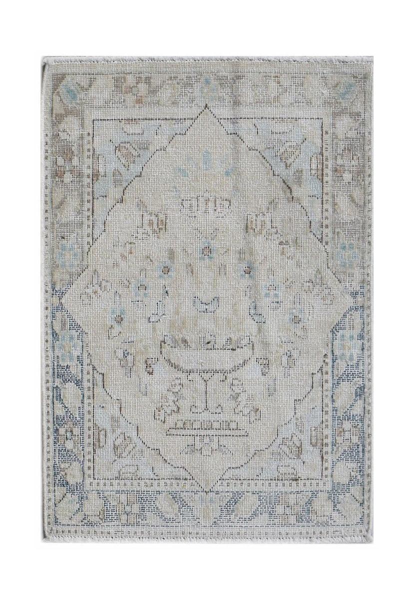 A mini vintage Persian Kerman rug featuring a central medallion and floral motifs in muted tones.