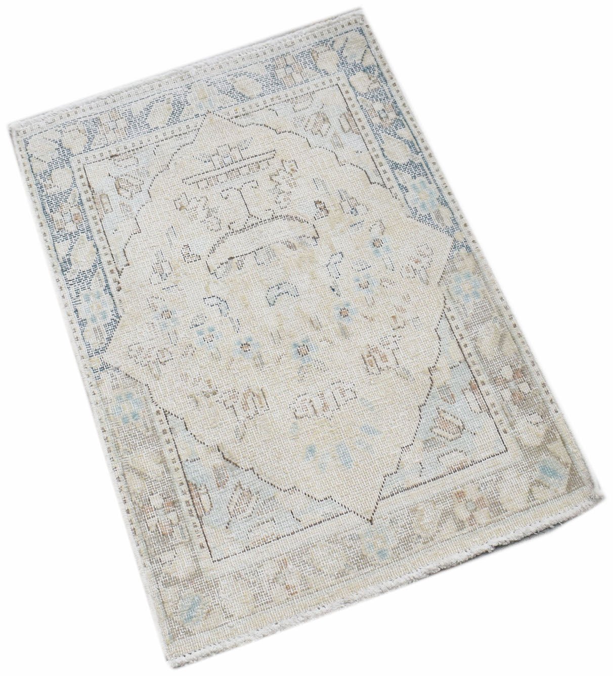 A mini vintage Persian Kerman rug featuring a central medallion in soft blue and beige tones.