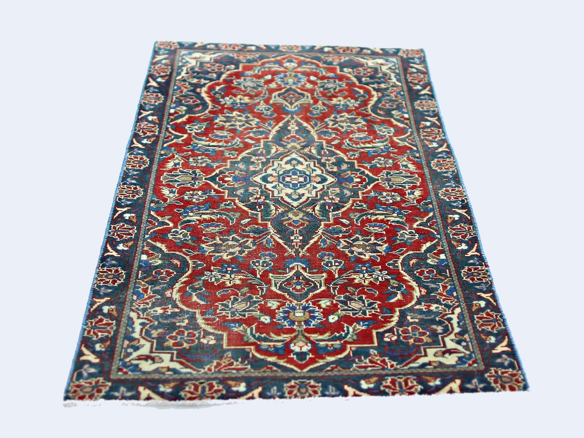 A rectangular vintage Persian rug featuring a traditional floral pattern in red and blue tones.