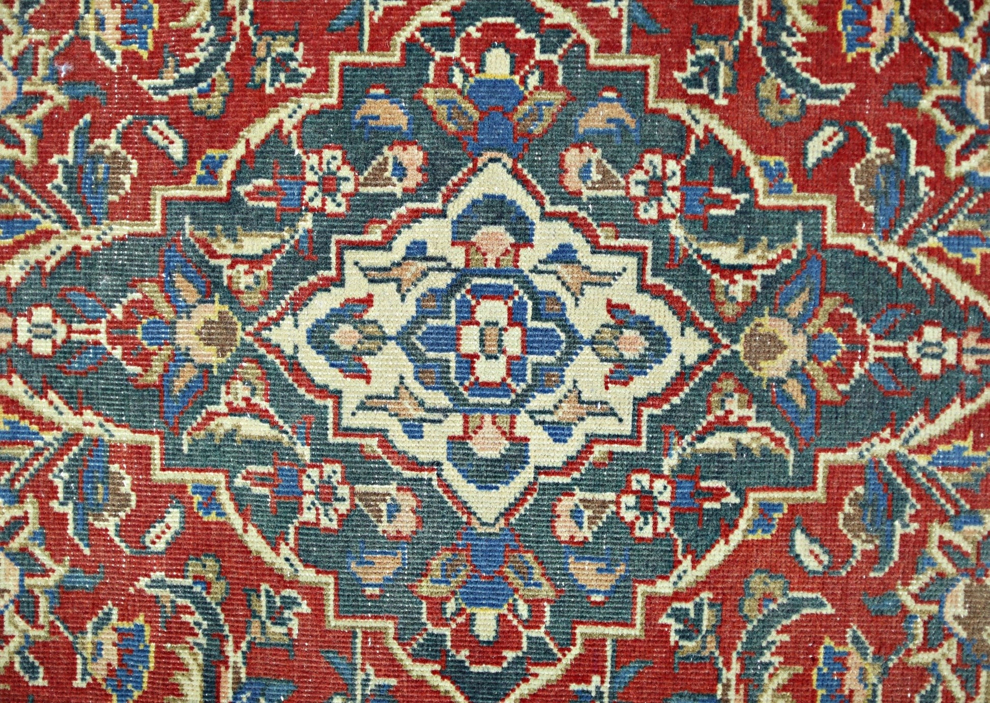 A vintage Persian rug featuring a central geometric medallion in blue, cream, and red tones.