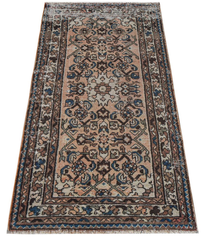 A handwoven vintage Persian runner rug featuring a floral pattern in muted peach, blue, and brown.