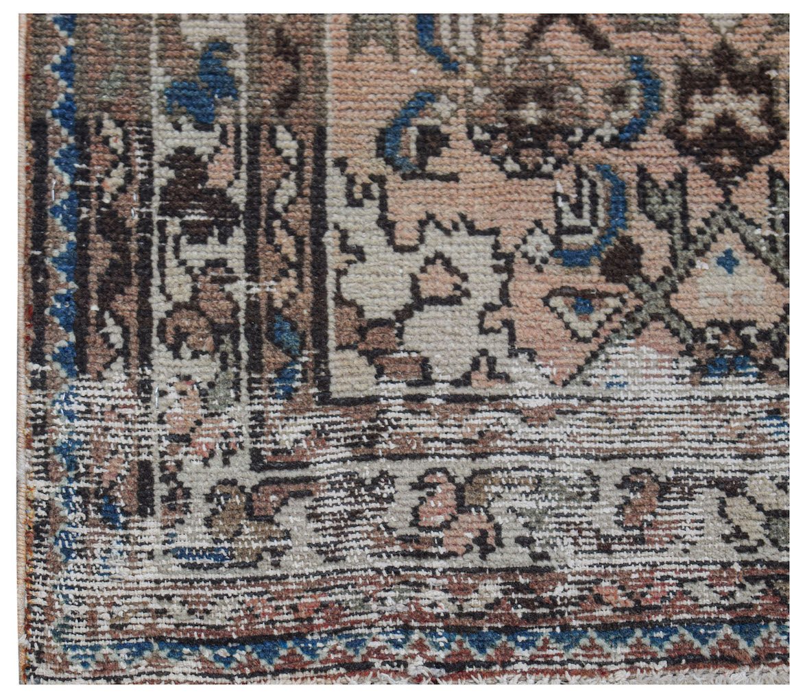 A close-up of a vintage Persian rug featuring intricate geometric patterns in muted earth tones.
