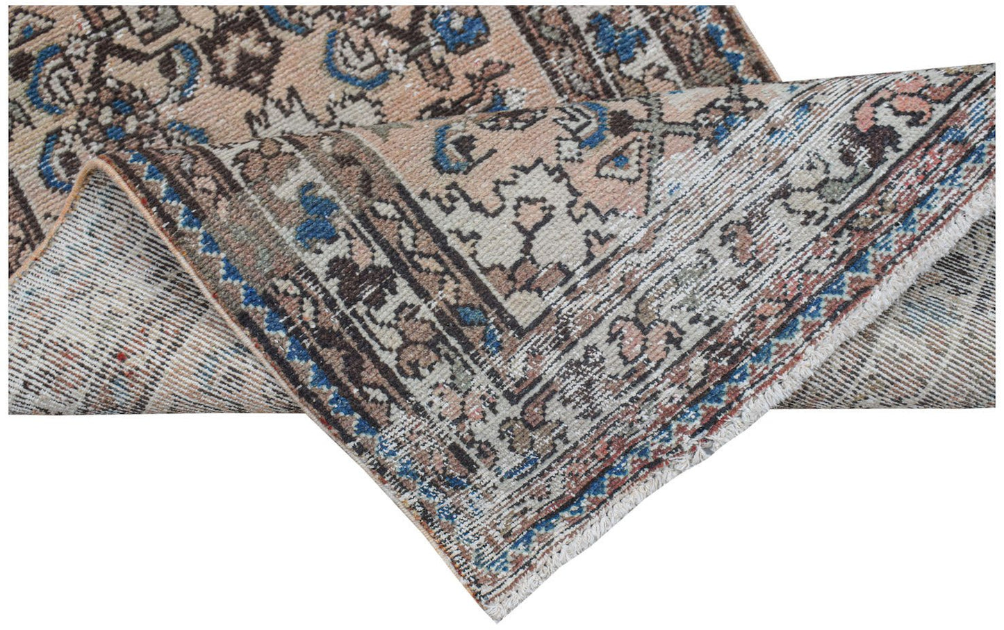 A handwoven vintage Persian rug with a faded floral pattern in blue, brown, and cream tones.