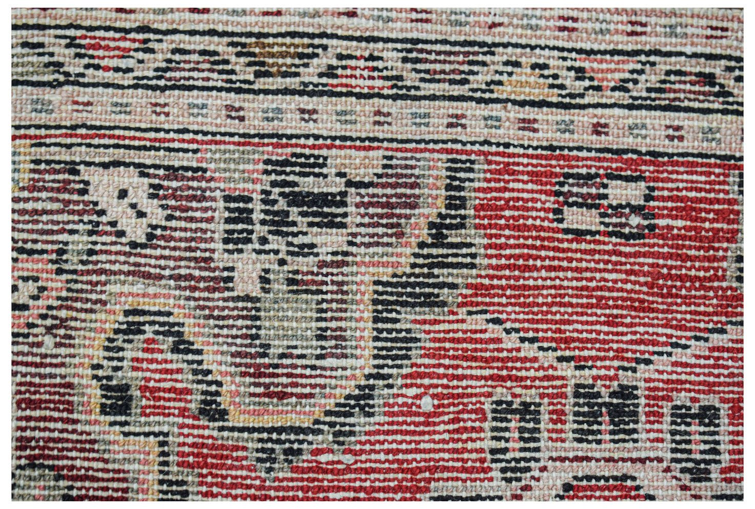 A close-up of a handwoven vintage Persian Sarouk rug featuring intricate red and black patterns.