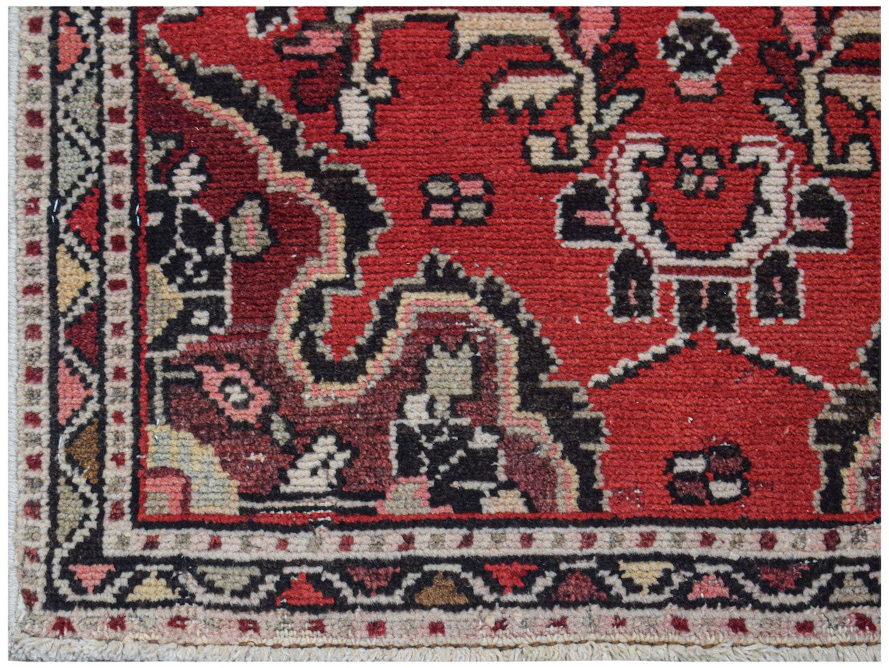 A vintage handwoven Persian Sarouk rug featuring a red field with intricate floral patterns.