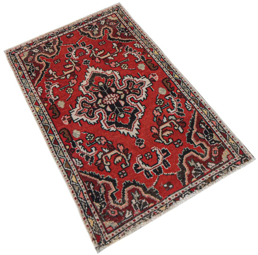 A handwoven vintage Persian Sarouk rug featuring a central floral medallion on a red field.