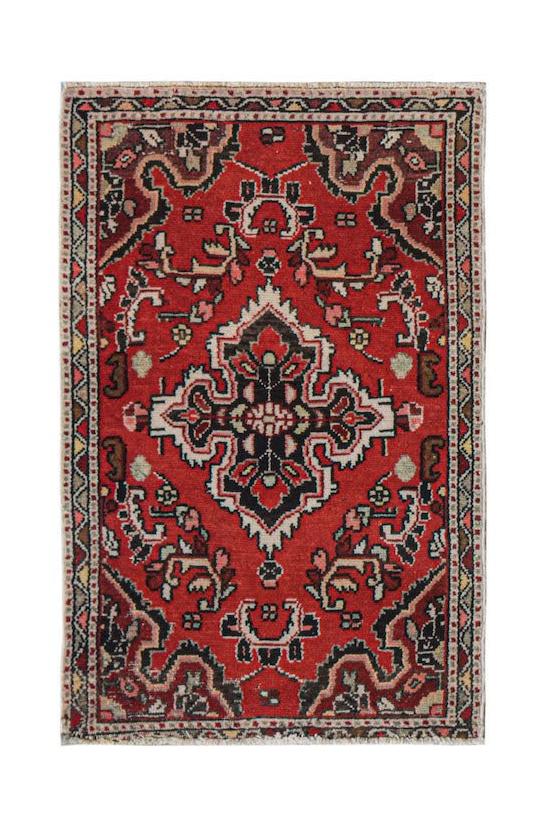 A rectangular vintage Persian Sarouk rug featuring a central floral medallion on a red field.