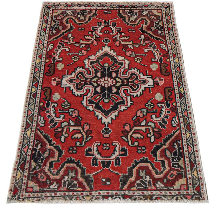 A handwoven vintage Persian Sarouk rug featuring a central floral medallion on a red field.