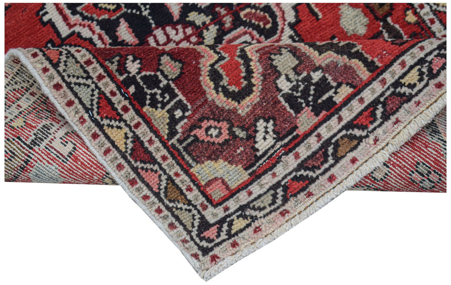 A folded vintage Persian Sarouk rug featuring a traditional floral pattern in red and black.