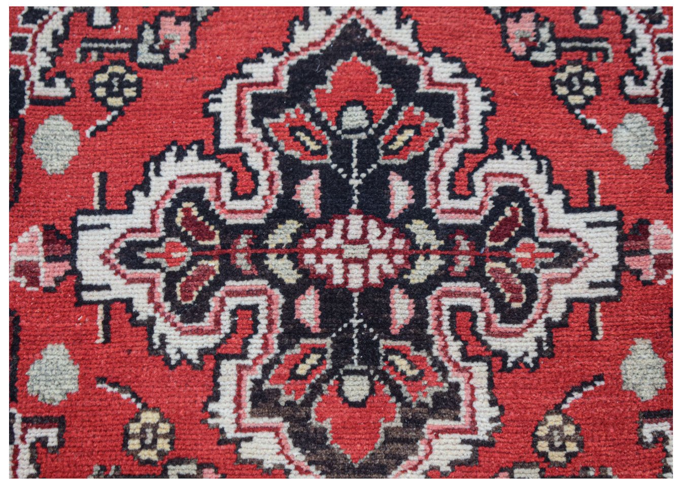 A vintage Persian Sarouk rug featuring a central floral medallion on a red wool background.
