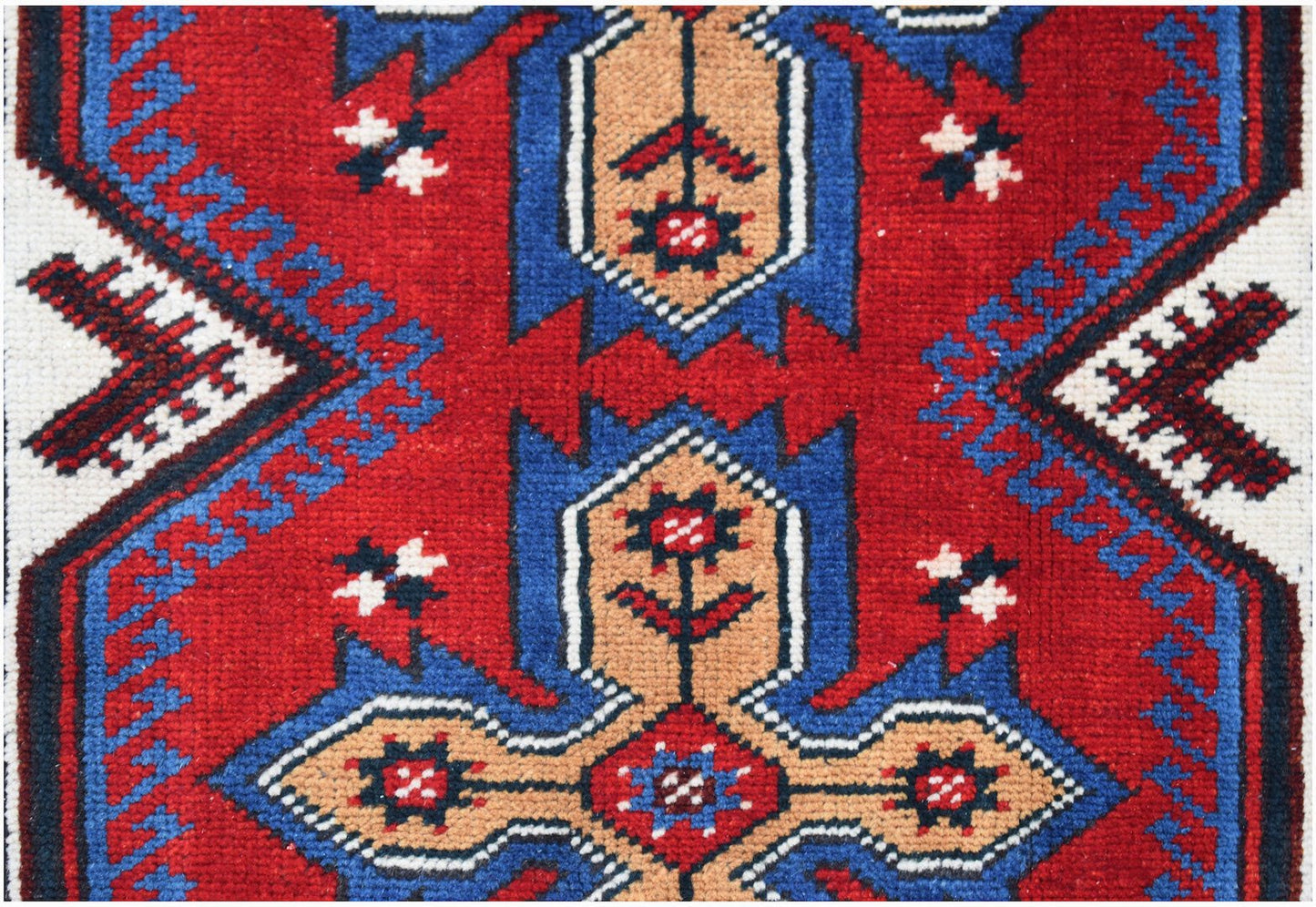 A handwoven vintage Turkish rug featuring a geometric floral pattern in red, blue, and tan.