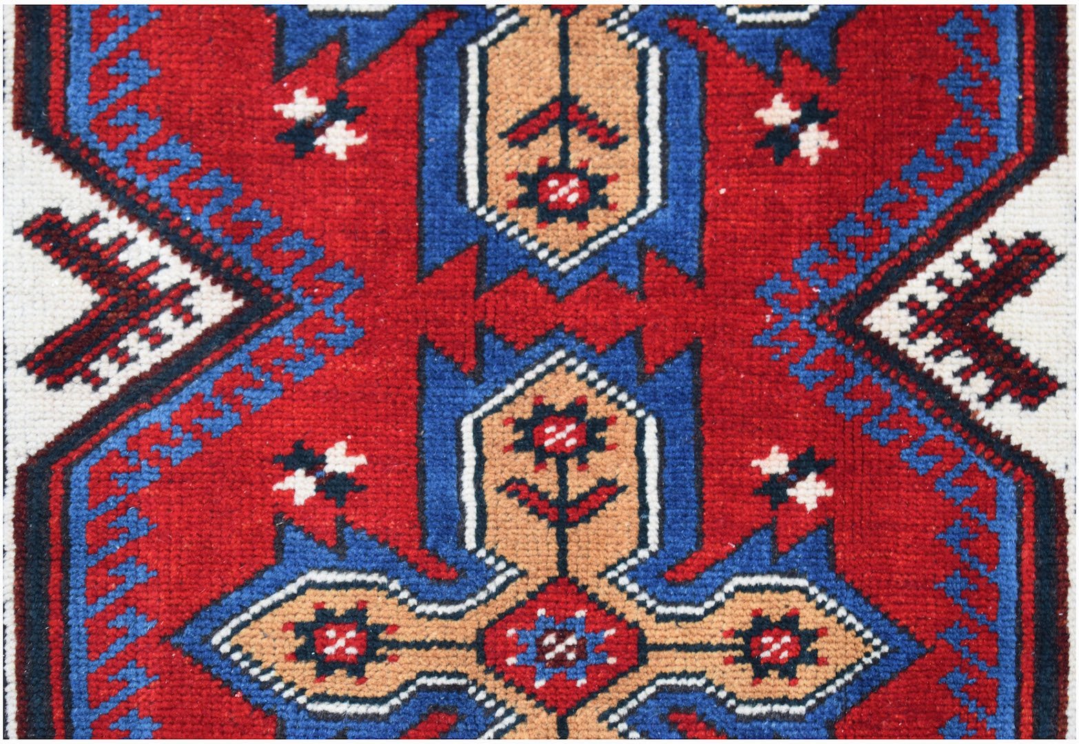 A handwoven vintage Turkish rug featuring a geometric floral pattern in red, blue, and tan.