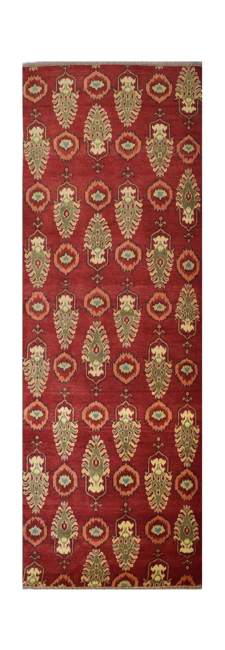 An Afghan Chobi runner rug featuring a repeating pattern of green and orange motifs on a red field.
