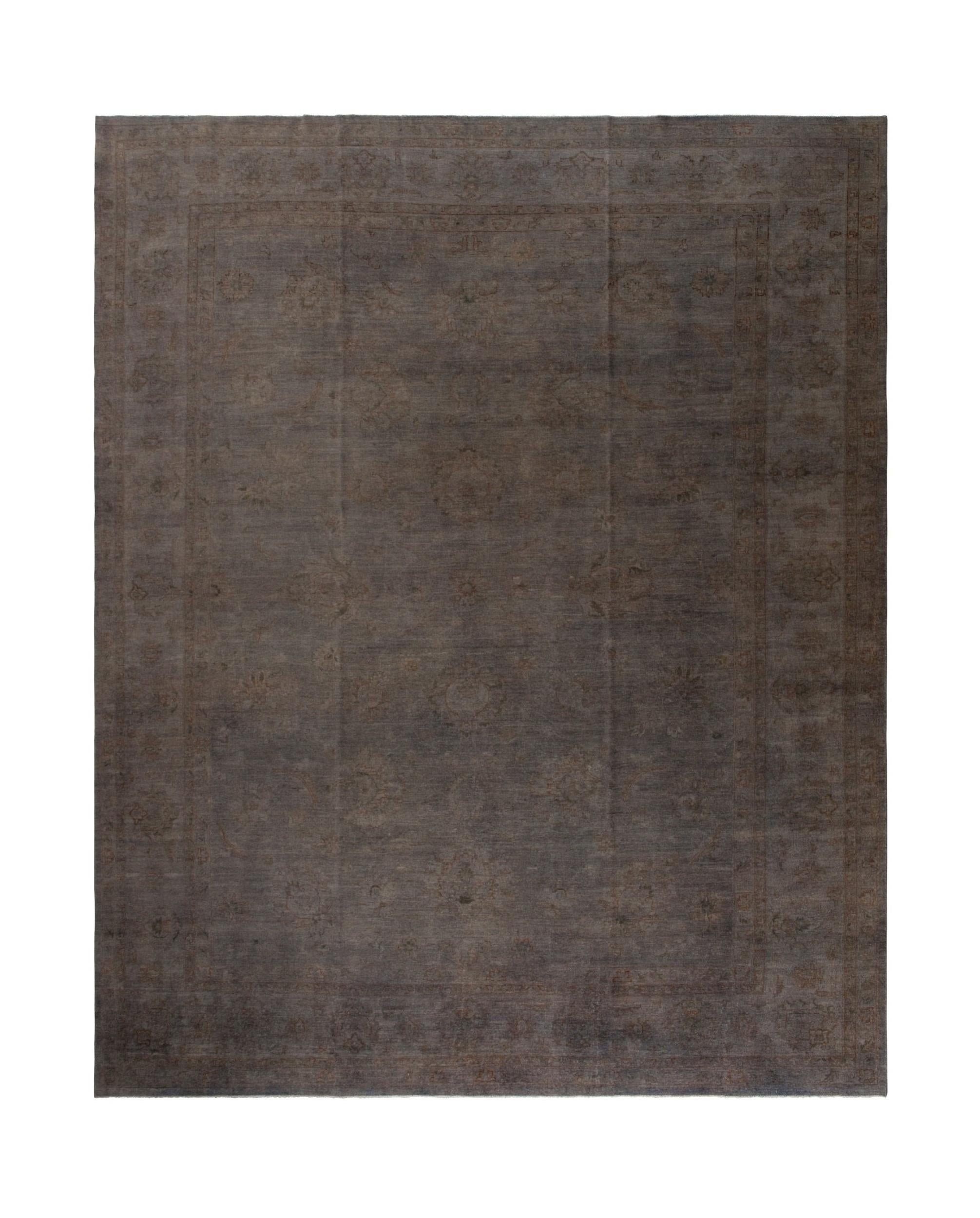 An overdyed Afghan Chobi rug featuring a subtle, traditional floral pattern in dark grey tones.