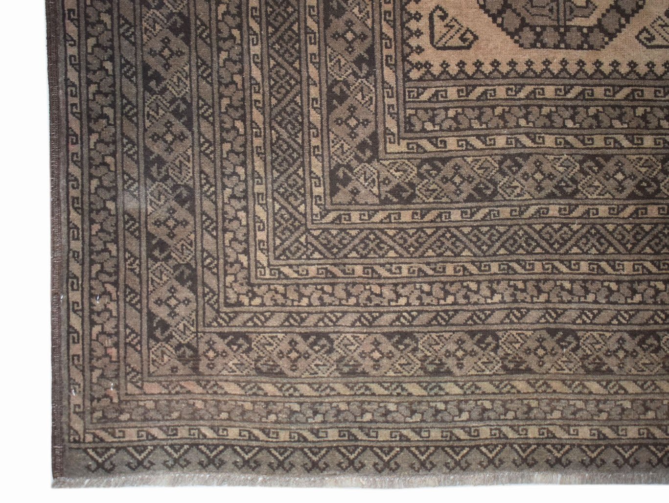 A vintage Afghan Turkmen rug featuring intricate geometric patterns in shades of brown and tan.
