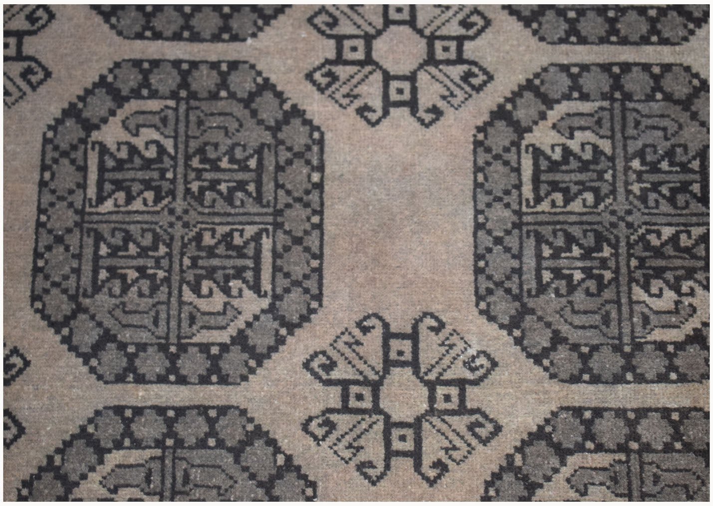 A vintage Afghan Turkmen rug featuring a repeating geometric pattern in shades of grey and brown.
