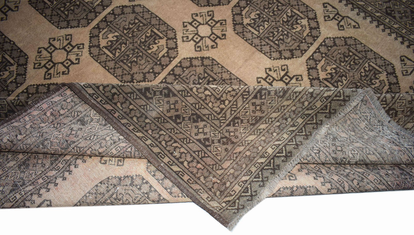 A vintage Afghan Turkmen rug with geometric patterns in brown and beige, shown folded.