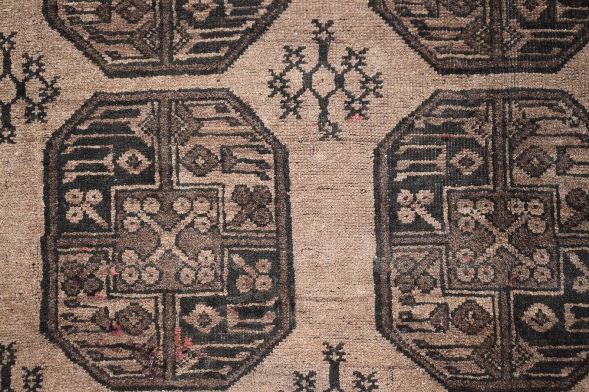 A vintage Afghan Turkmen rug featuring dark geometric octagonal motifs on a tan wool background.