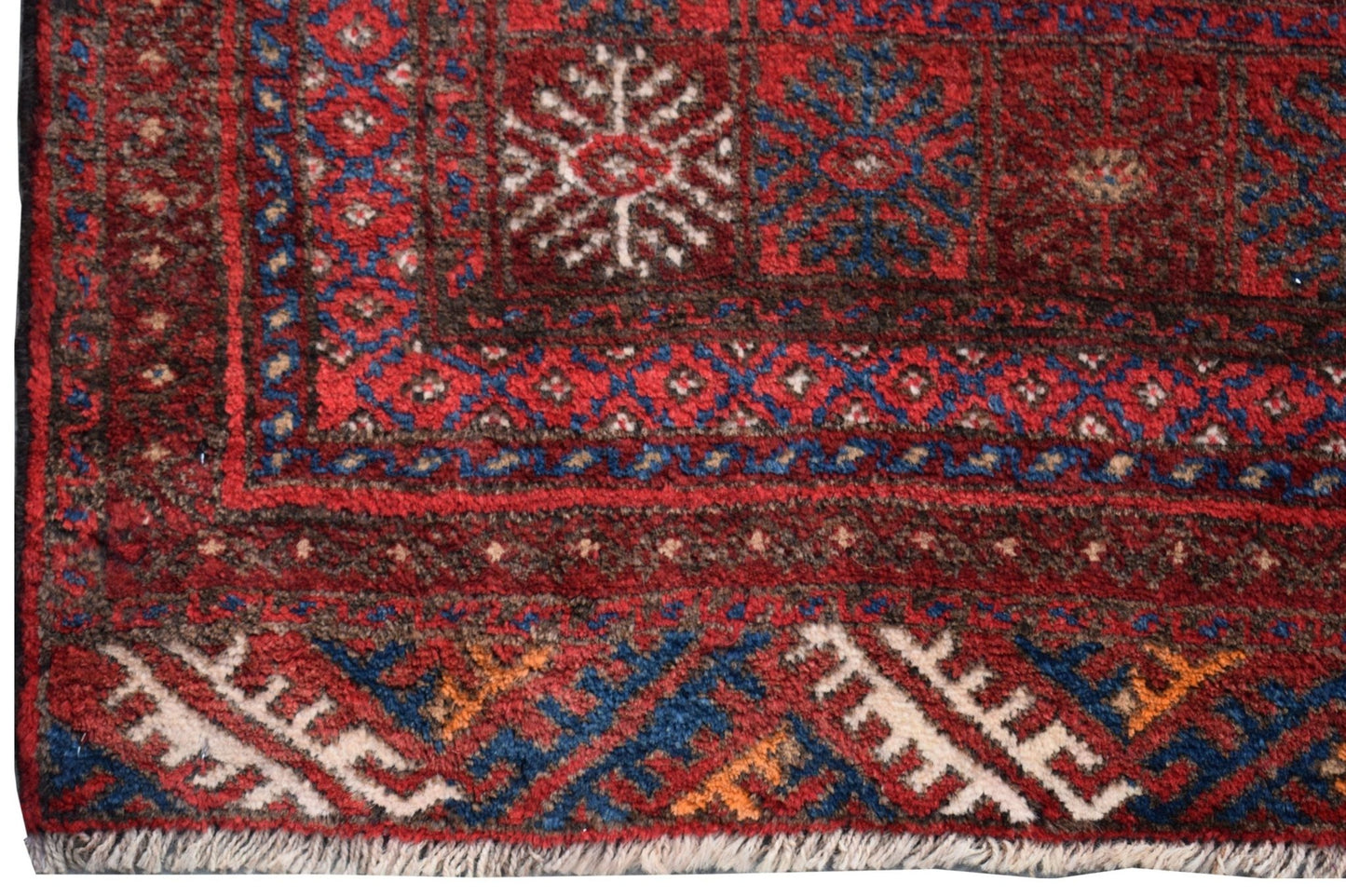 A vintage Afghan Baluch rug featuring traditional geometric patterns in red, blue, and white wool.