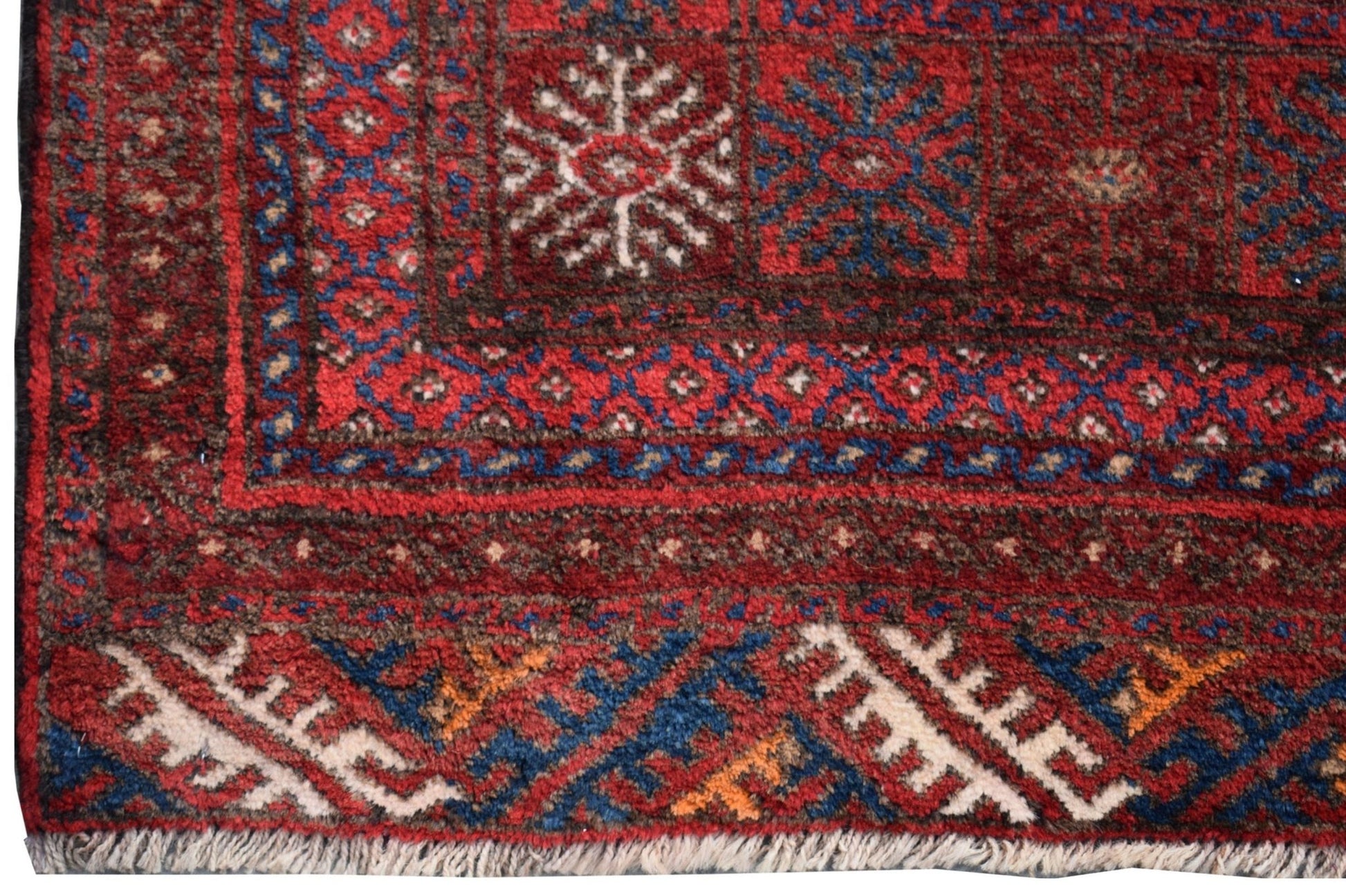 A vintage Afghan Baluch rug featuring traditional geometric patterns in red, blue, and white wool.