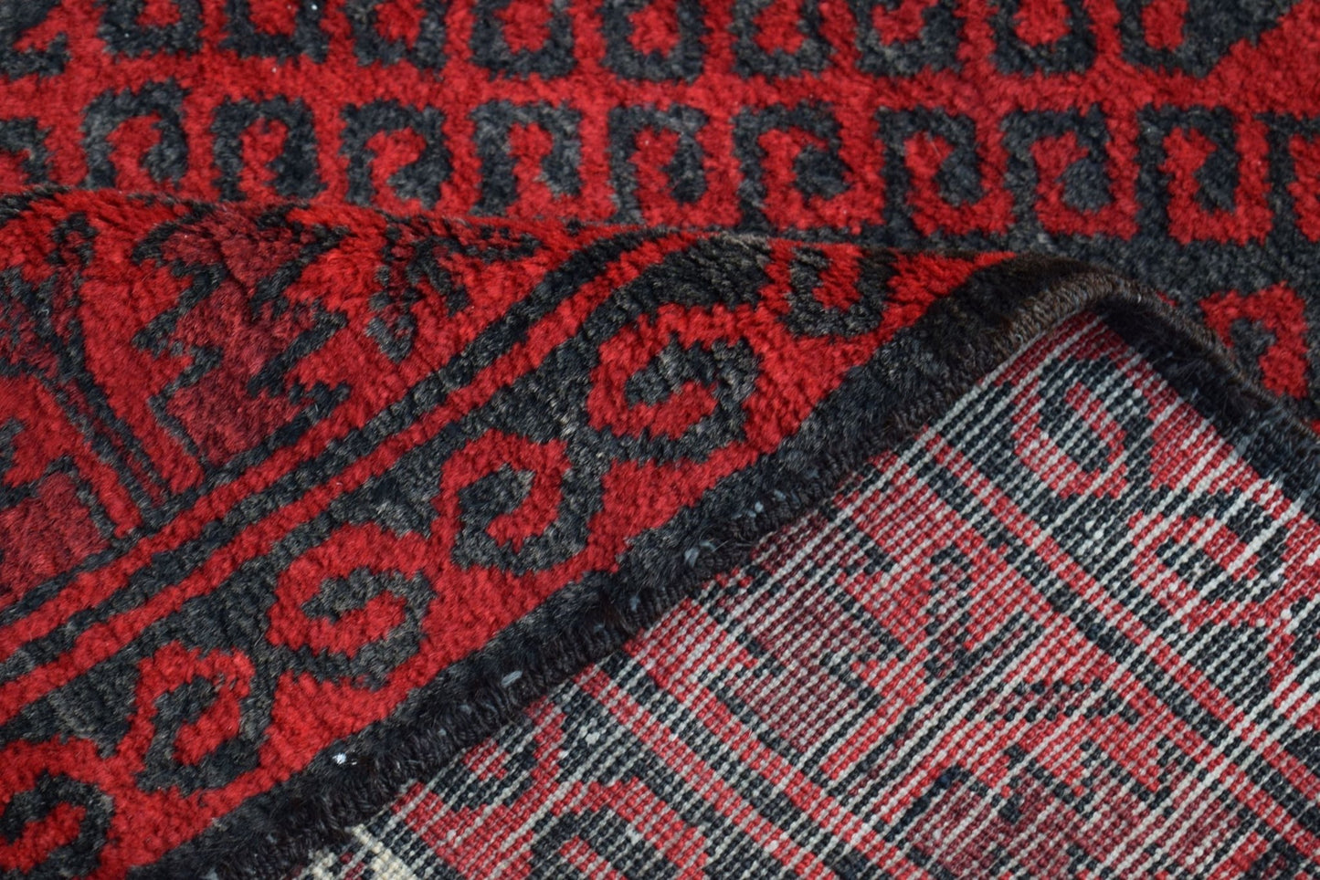 A vintage handmade Afghan Baluch rug featuring a red and black geometric pattern.