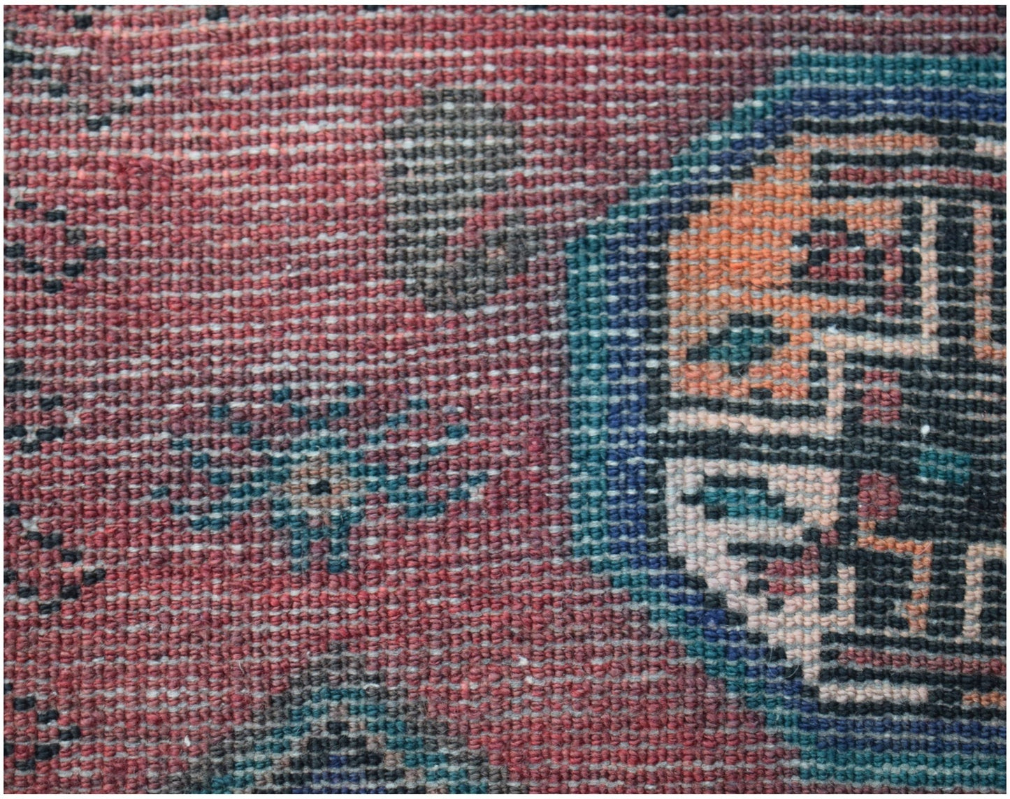 A close-up of a vintage Afghan Baluch rug featuring a geometric pattern in red, blue, and orange.