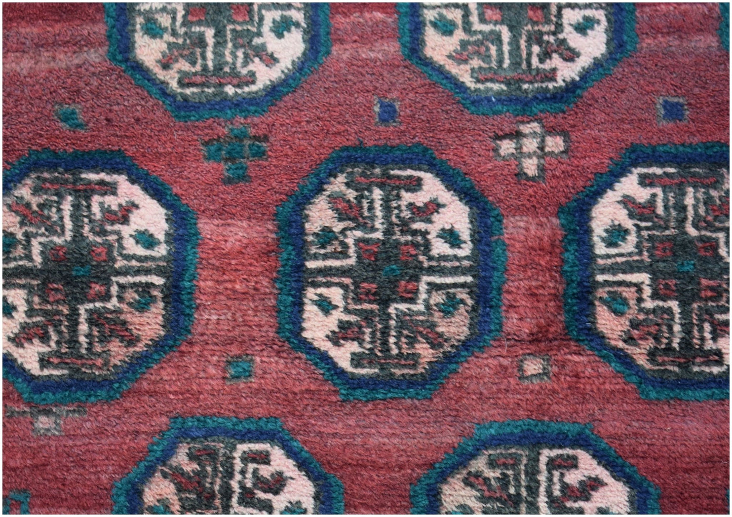 A vintage Afghan Baluch rug featuring repeating geometric octagonal motifs in red, blue, and cream.
