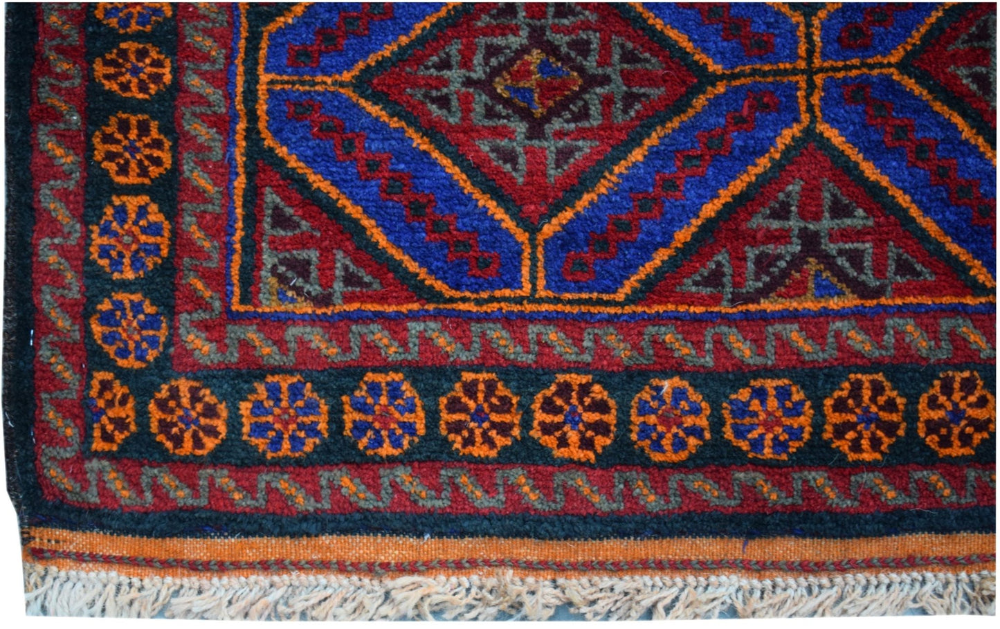 A vintage Afghan Baluch wool rug featuring a geometric diamond pattern in red, blue, and orange.