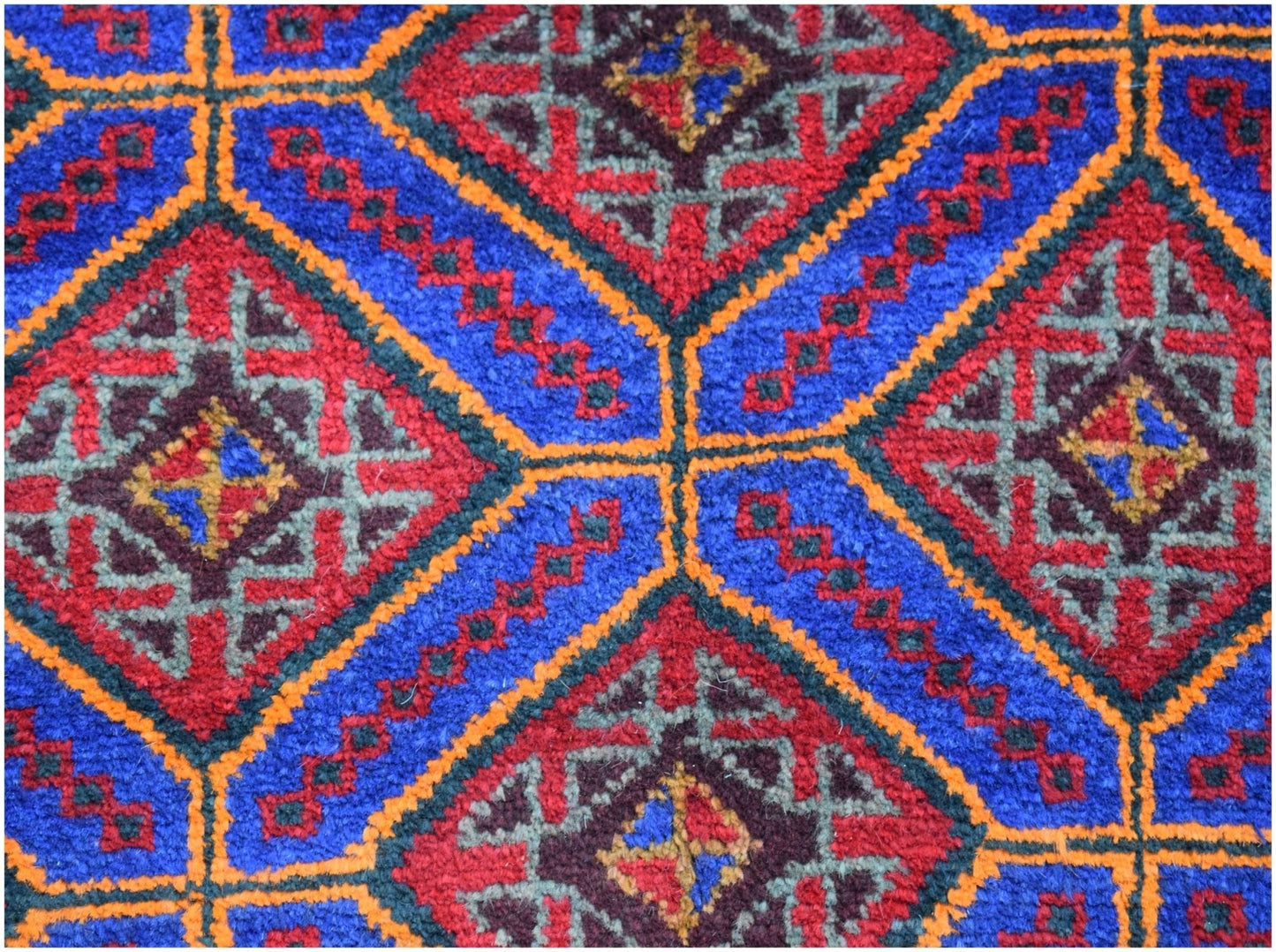 A vintage Afghan Baluch wool rug featuring a geometric pattern of red and blue diamonds.